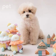 Small fluffy dog sitting next to BITE ME Long-Lasting Nosework Clown Toy with pastel colors and wooden blocks nearby